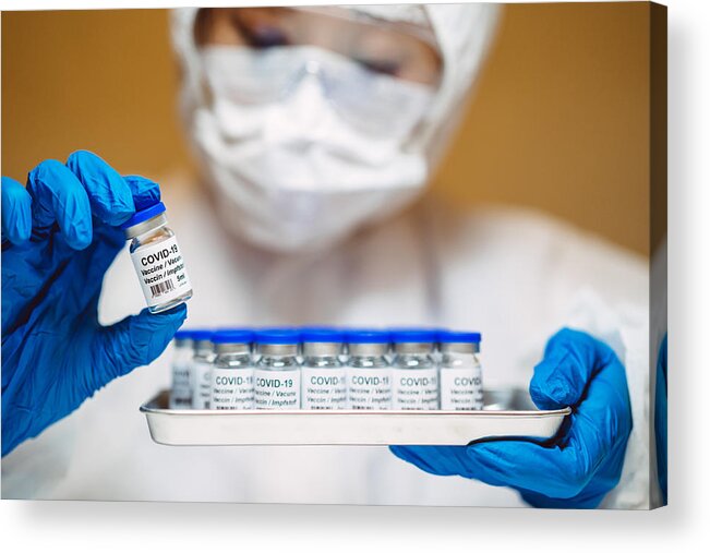 Expertise Acrylic Print featuring the photograph Healthcare professional in protective gloves & workwear holding & organising a tray of COVID-19 vaccine vials by Images By Tang Ming Tung