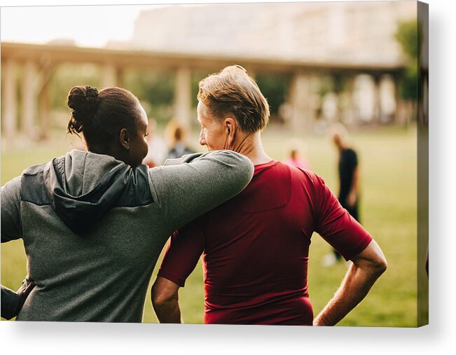 Mature Adult Acrylic Print featuring the photograph Man and woman talking while looking at senior friends in park by Maskot
