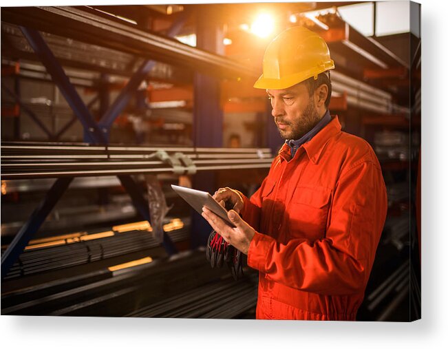 Mid Adult Acrylic Print featuring the photograph Manual worker using digital tablet in industrial building. by BraunS