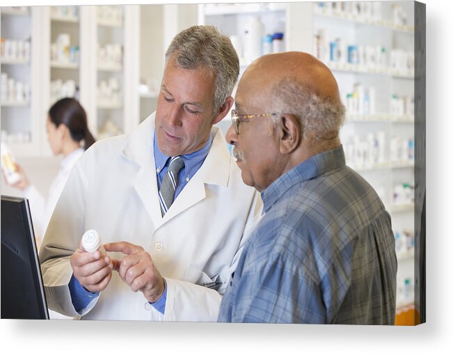 Expertise Acrylic Print featuring the photograph Pharmacist talking to customer about prescription by Ariel Skelley