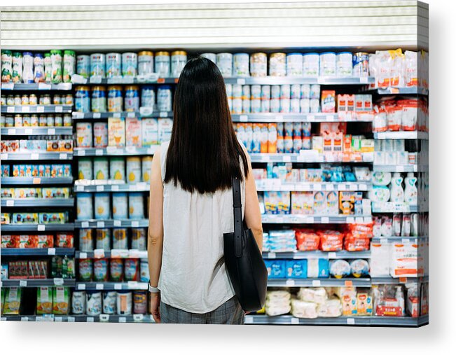 Confusion Acrylic Print featuring the photograph Rear view of young Asian mother groceries shopping for baby products in a supermarket. She is standing in front of the baby product aisle and have no idea which product to choose from by D3sign