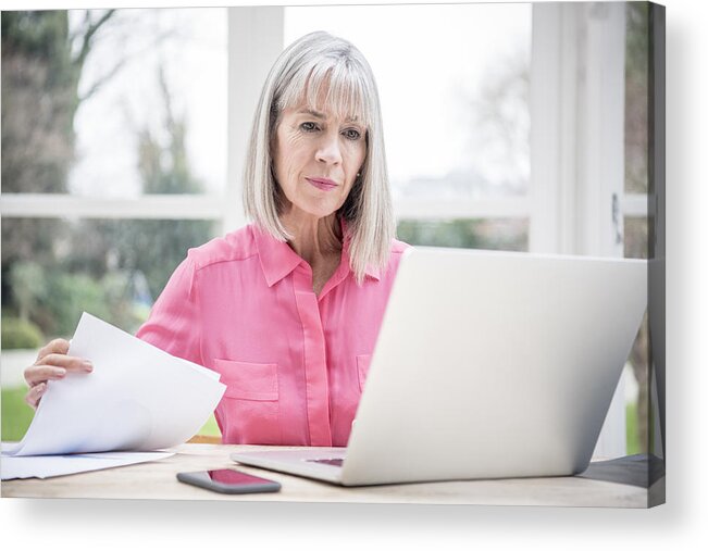 Confusion Acrylic Print featuring the photograph Serious looking senior woman with laptop and paperwork by JohnnyGreig