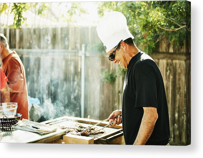 Expertise Acrylic Print featuring the photograph Smiling father grilling in backyard during family barbecue by Thomas Barwick