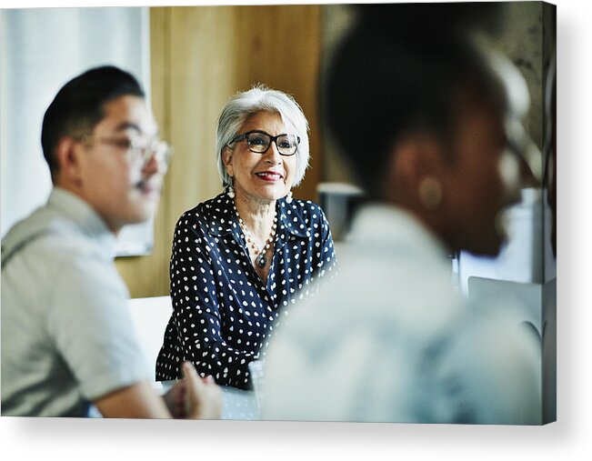 Young Men Acrylic Print featuring the photograph Smiling mature female business owner listening during presentation during meeting in office conference room by Thomas Barwick
