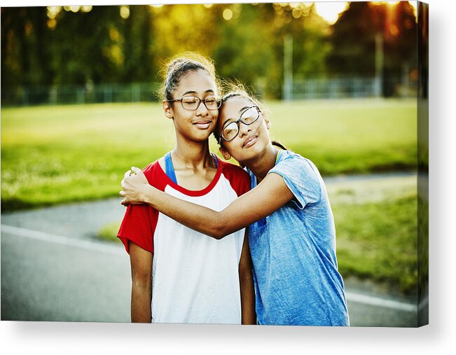 Outdoors Acrylic Print featuring the photograph Twin sisters embracing on basketball court by Thomas Barwick