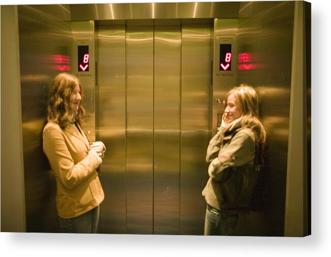 Three Quarter Length Acrylic Print featuring the photograph Two young women waiting in elevator by Photodisc