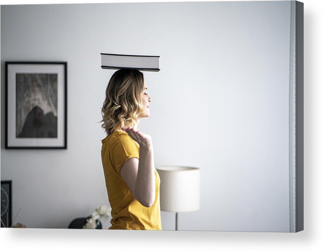 Mid Adult Acrylic Print featuring the photograph Woman at home balancing a book on her head by Westend61