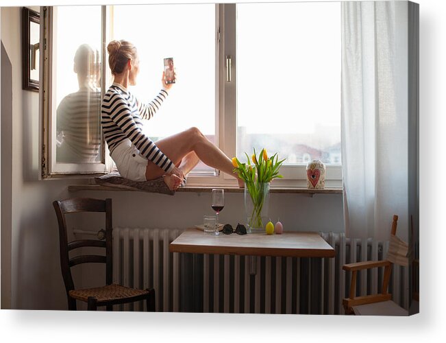 People Acrylic Print featuring the photograph Woman sitting on a windowsill, video chatting with family member by Kathrin Ziegler