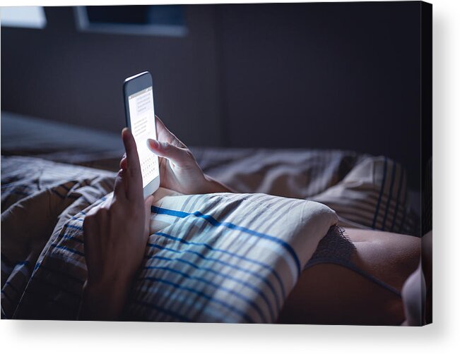 Hipster Culture Acrylic Print featuring the photograph Woman using phone late at night in bed. Person looking at text messages with cell in dark home. Hipster online dating or texting with smartphone. Sexting or cheating concept. by Tero Vesalainen