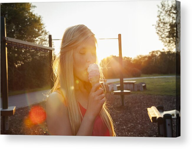 Outdoors Acrylic Print featuring the photograph Young woman eating ice cream cone in park at sunset by Manuela