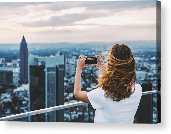 Wind Acrylic Print featuring the photograph Woman taking photo with mobile phone above city #1 by Xsandra