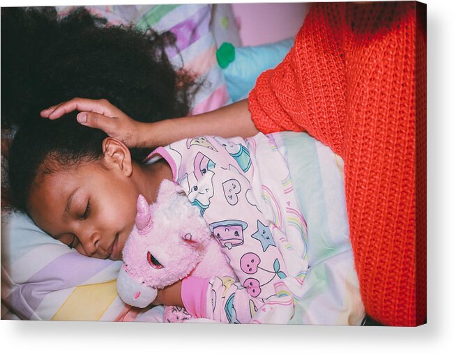 Child Acrylic Print featuring the photograph Afrolatina girl in pajamas holding stuffed unicorn with her eyes closed. Mother's face and neck not visible. Mother's hand on daughters head. by Evelyn Martinez