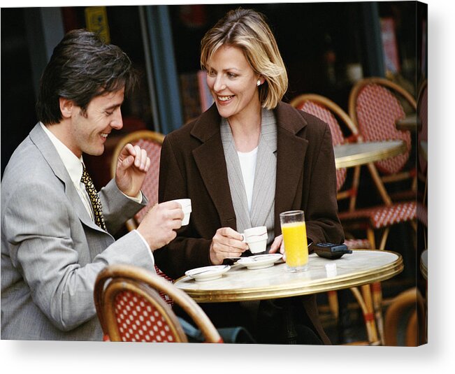 Mid Adult Men Acrylic Print featuring the photograph Businessman and businesswoman having coffee at cafe terrace by Eric Audras