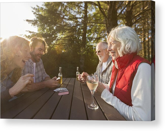 Mid Adult Men Acrylic Print featuring the photograph Senior couple and adult children playing cards at campsite picnic table by Compassionate Eye Foundation/Steven Errico