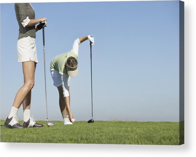 Putting Green Acrylic Print featuring the photograph Two Women Standing on a Putting Green, One Picking Up a Golf Ball by John Cumming