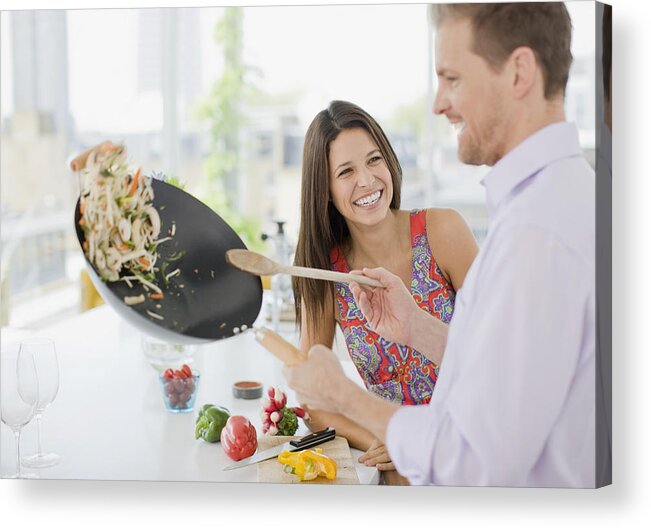 Heterosexual Couple Acrylic Print featuring the photograph Woman watching husband flipping stirfry in the kitchen by Paul Bradbury