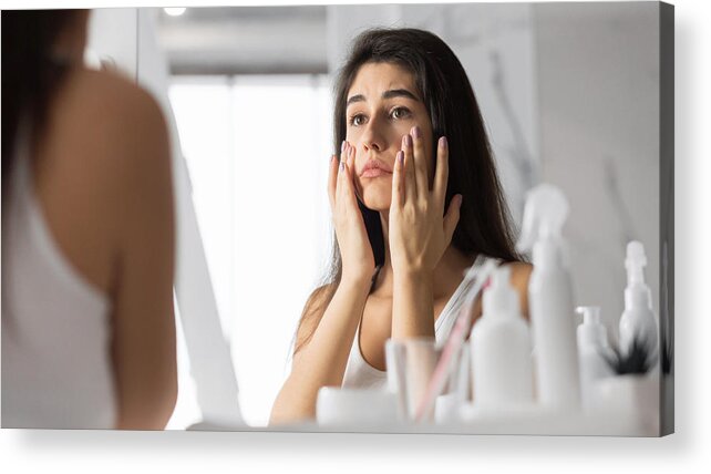 Spa Acrylic Print featuring the photograph Woman Touching Face Looking At Skin In Mirror At Bathroom by Prostock-Studio