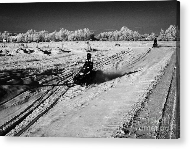 Man Acrylic Print featuring the photograph two men on snowmobiles crossing frozen fields in rural Forget Saskatchewan Canada by Joe Fox