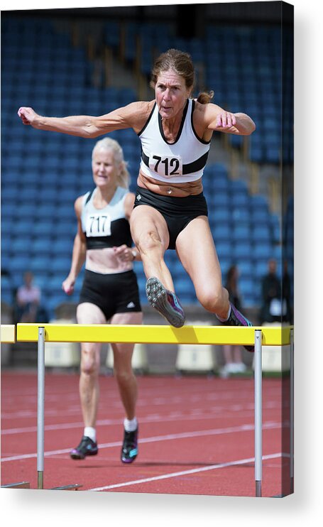 One Person Female Acrylic Print featuring the photograph Senior Female Athlete Clears Hurdle by Alex Rotas