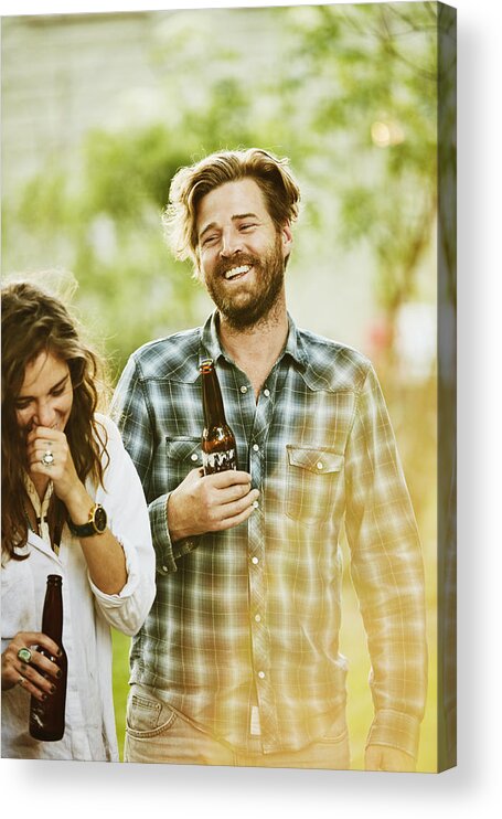 Plaid Shirt Acrylic Print featuring the photograph Laughing friends sharing drinks during backyard party on summer evening by Thomas Barwick