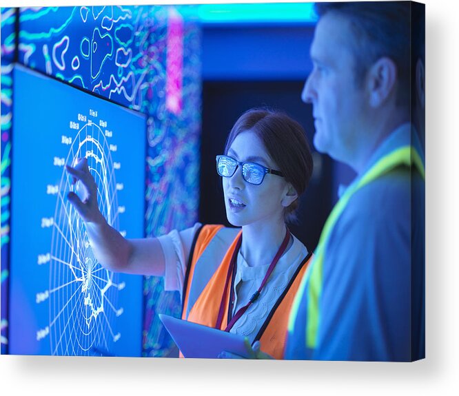 Working Acrylic Print featuring the photograph Female geologist with colleague studying graphical display of oil and gas bearing rock on screens by Monty Rakusen