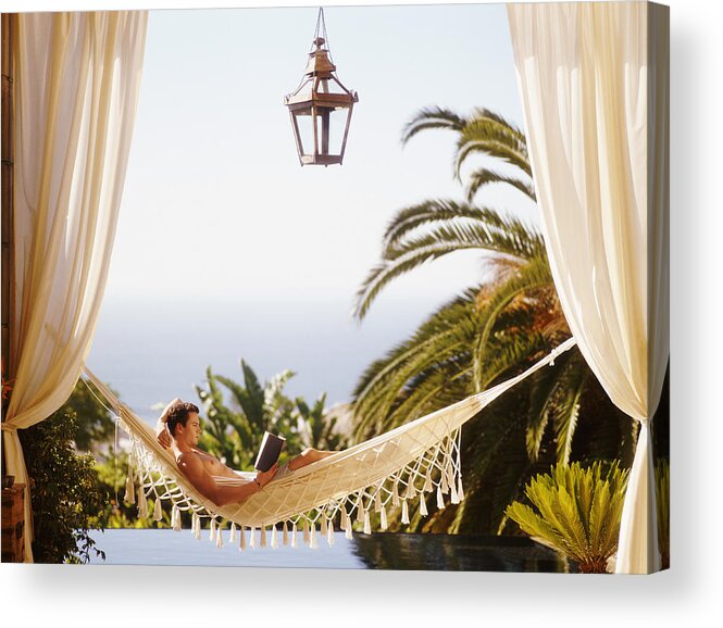 Hands Behind Head Acrylic Print featuring the photograph Man Lying in Hammock Reading a Book by Flying Colours Ltd