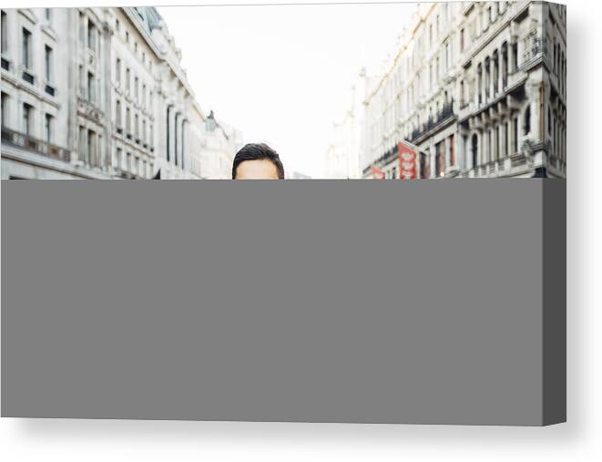 Young Men Canvas Print featuring the photograph Young happy smiling man in glasses on the streets of London, UK #1 by Alexander Spatari