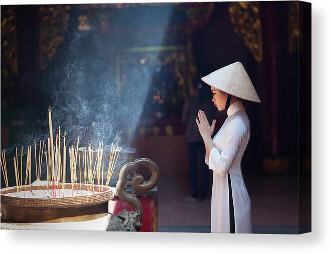Ho Chi Minh City Canvas Print featuring the photograph A Girl In Ao Dai Praying In A Pagoda by Jethuynh