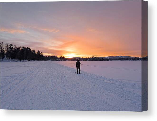 Ski Pole Canvas Print featuring the photograph A man skiing into the sunset by Sami Hurmerinta