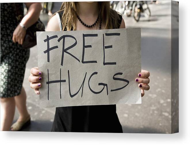 Zurich Canvas Print featuring the photograph A young woman holding a sign saying Free Hugs by Tobias Titz