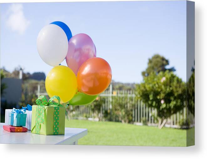 Celebration Canvas Print featuring the photograph Balloons and birthday presents on table in garden by Image Source