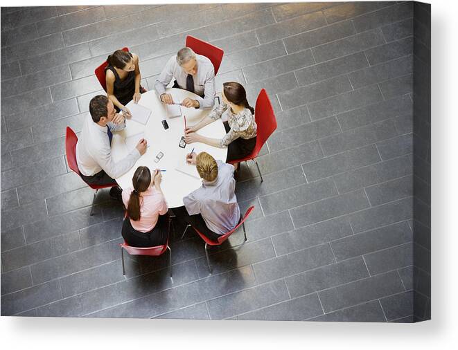 Working Canvas Print featuring the photograph Business people having a meeting at round table by Daly and Newton