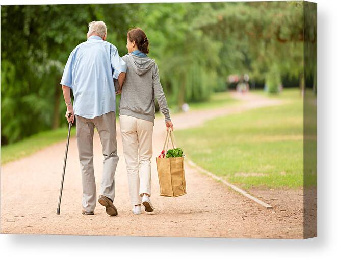 Mature Adult Canvas Print featuring the photograph Caregiver – woman helping senior man with shopping by FredFroese