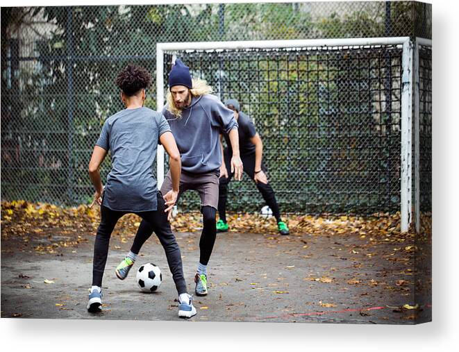 Young Men Canvas Print featuring the photograph Confident man dribbling ball from opponent by Alvarez