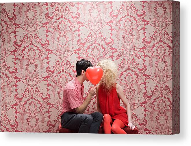 Young Men Canvas Print featuring the photograph Couple behind heart shaped balloon by Image Source