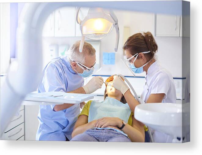 Working Canvas Print featuring the photograph Dental team performing procedure by Sturti