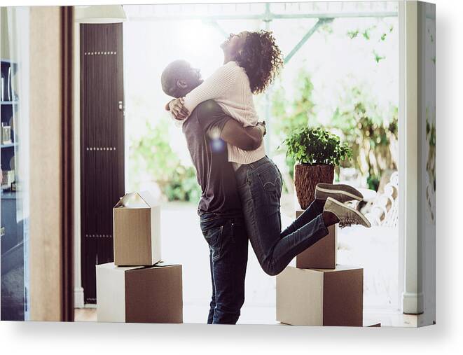 Young Men Canvas Print featuring the photograph Happy man lifting woman in new house by Portra