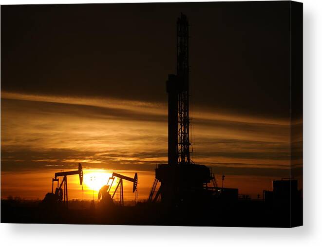 Williston. North Dakota Canvas Print featuring the photograph Oil rig and two pumpjacks in the sunset by Jeff Swan