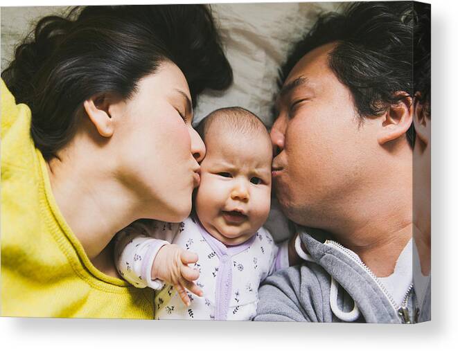 Asian And Indian Ethnicities Canvas Print featuring the photograph Parents kissing baby by Tuan Tran