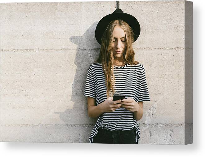 Shadow Canvas Print featuring the photograph Portrait of fashionable young woman wearing hat using smartphone by Westend61