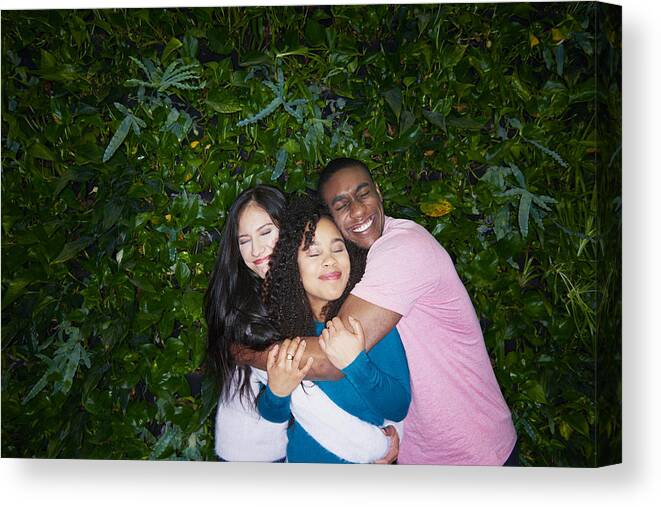 Young Men Canvas Print featuring the photograph Three Young Adults Hugging by Tara Moore