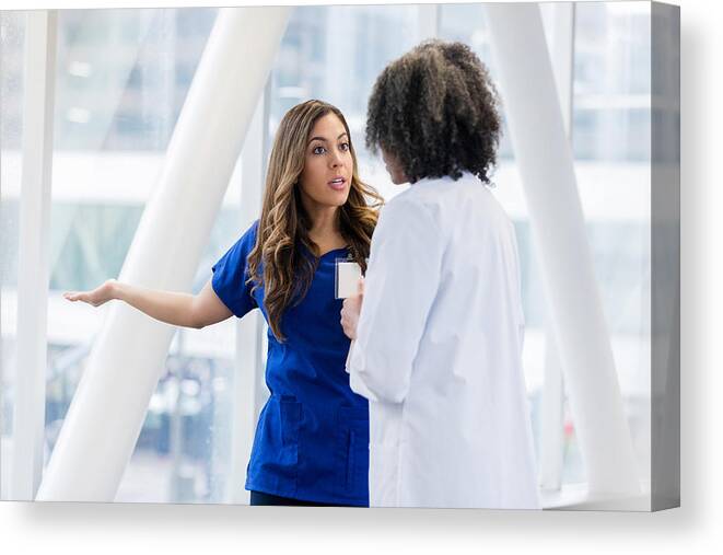 Elevated Walkway Canvas Print featuring the photograph Upset female healthcare professional talks with colleage by SDI Productions