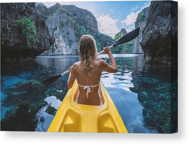 Tranquility Canvas Print featuring the photograph View of a young woman canoeing in beautiful tropical lagoon by Swissmediavision