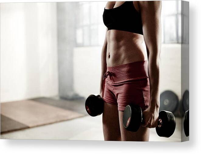 People Canvas Print featuring the photograph Woman holding dumbbells in gym. by Mike Harrington