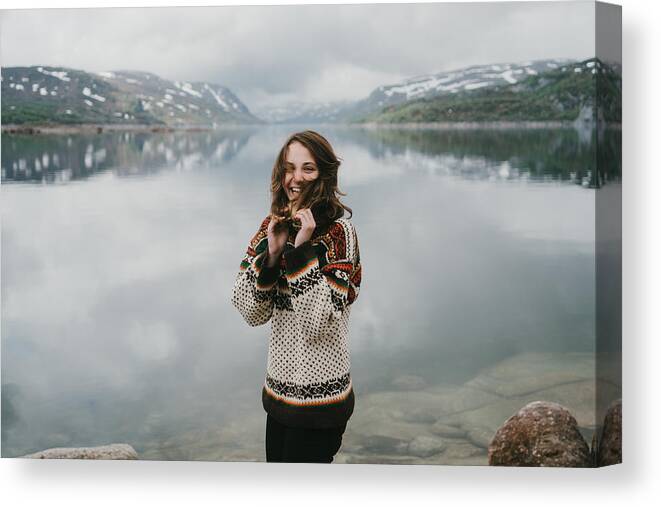 Tranquility Canvas Print featuring the photograph Woman in knitted sweater laughing near the fjord in Norway by Oleh_Slobodeniuk