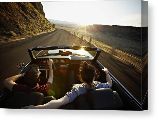 Young Men Canvas Print featuring the photograph Young couple driving convertible at sunset by Thomas Barwick