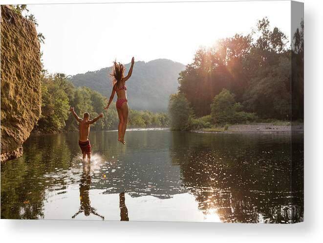 Young Men Canvas Print featuring the photograph Young Couple Jumping Into River by Zave Smith