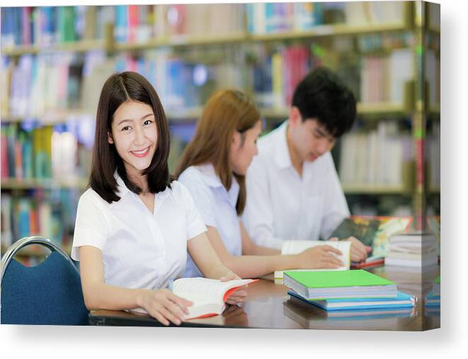 College Canvas Print featuring the photograph Asian student lady smile and read a book in library in universit by Anek Suwannaphoom
