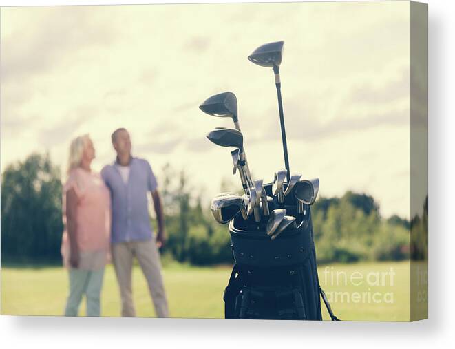Golf Canvas Print featuring the photograph Golf bag standing on a grass field, people in the background by Michal Bednarek