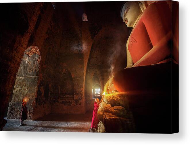 Monk Canvas Print featuring the photograph Monk in Bagan old town pray a buddha statue with candle by Anek Suwannaphoom